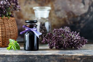 Oregano essential oil in glass bottle on wooden background.