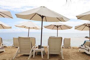 beach chairs under white beach umbrellas with a beautiful Balinese beach in the background. the...