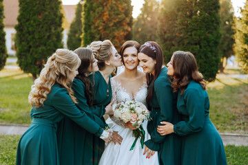 Wedding photography. A brunette bride in a wedding dress and her friends in emerald dresses