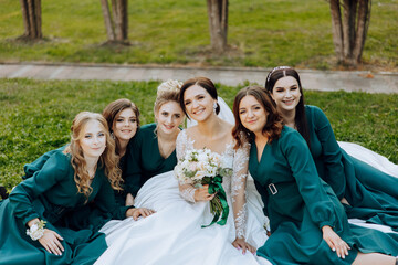 Wedding photography. A brunette bride in a wedding dress and her friends in emerald dresses