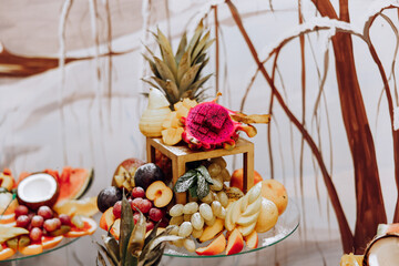 A banquet table full of fruits and berries, an assortment of sweets. Bananas, grapes, pineapples. Fruit compositions for the holiday.