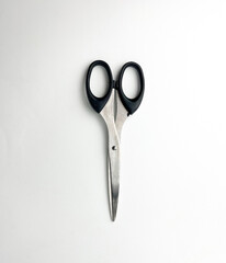 Stainless steel closed scissors with black colored handle. Cutting object photography isolated on plain studio background.
