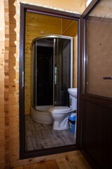 Bathroom with shower, toilet, and sink in wooden house