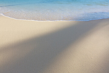 Fototapeta na wymiar Travel background with soft wave of blue ocean on sandy beach.