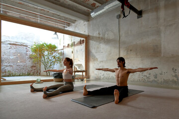 Couple doing yoga on mats in studio