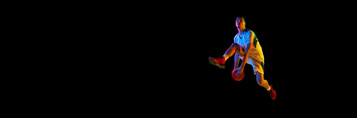 Banner. Young basketball player in motion in neon light against black background with negative space to insert your text. Concept of sport, energy, strength and power, match, championship, tournament.