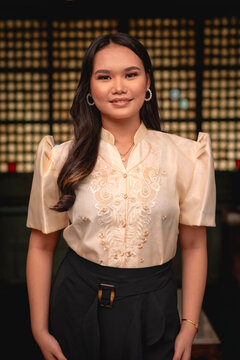Portrait of a young woman smiling in traditional Filipino clothing, showcasing detailed embroidery.