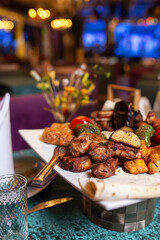assorted different kebabs on a white plate in a restaurant