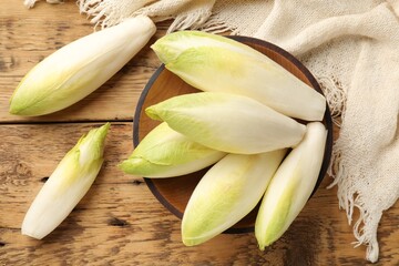 Fresh raw Belgian endives (chicory) and bowl on wooden table, top view - obrazy, fototapety, plakaty