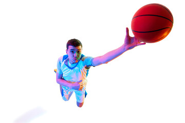 Overhead view of basketball player reaching out for slam dunk with enthusiasm against white studio background in neon light. Concept of professional sport, energy,match, championship, tournament.