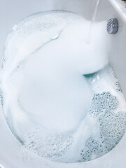 Modern White Bathtub Filled with Running Water from a Brushed Nickel Faucet