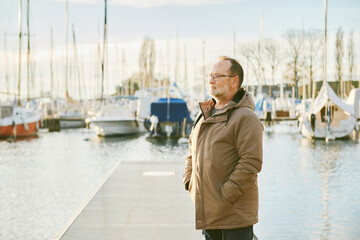 Outdoor portrait of happy mature man enjoying nice cold day by the lake or see - 741618834