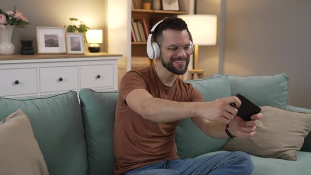 One adult man play video games use mobile phone smartphone at home