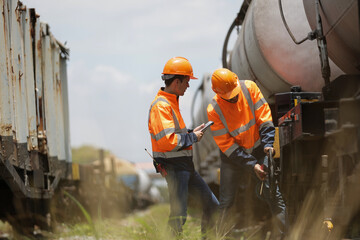 Two male logistic engineers work together on a freight train tanker for crude oil or chemical cargo.