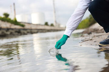 Male  biologist taking a water sample from factory 
