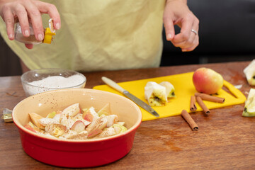 Hands sprinkle cinnamon on apples. Cooking apple pie.
