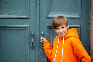 A teenage boy opens a closed door and looks at the camera.