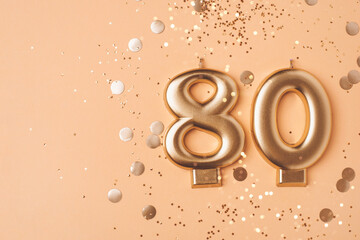 80 years celebration. Greeting banner. Gold candles in the form of number eighty on peach...