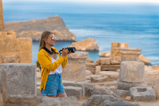 A woman tourist with a camera in the Acropolis on an excursion.