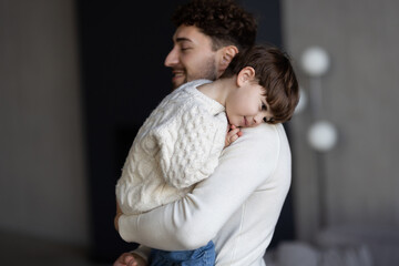 Loving young father and cute little preschooler son hug cuddle enjoying family weekend at home...