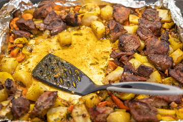 Roast meat and potatoes on a baking sheet. Includes a spatula and aluminum foil for baking....