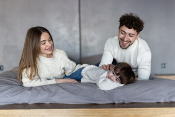 Parents playing with their kid in the bed