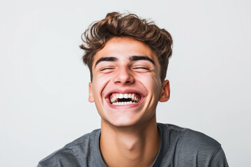 Joyful young man laughing against plain background. Expression of happiness and positivity.