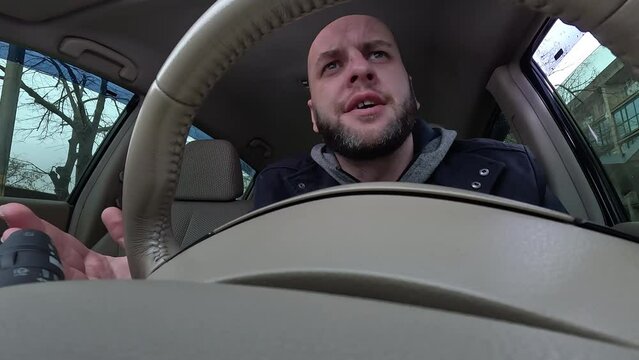 Angry screaming car driver yells furiously while going out onto the road while standing in a traffic jam waiting in line