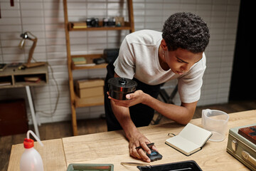 Engrossed in film development, dark skinned man meticulously times the process in a darkroom