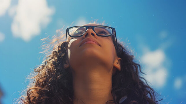 Portrait of a young woman with glasses against the blue sky.