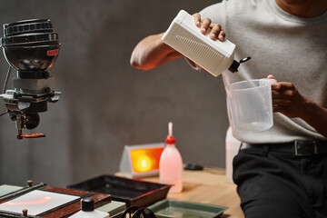 partial, african american man pouring chemical solution in measuring cup, analog film development