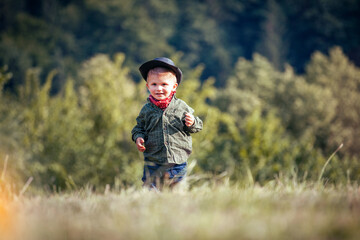 Cute Little Happy Boy with Hat and Bandana in Green Summer Forest - 741650488