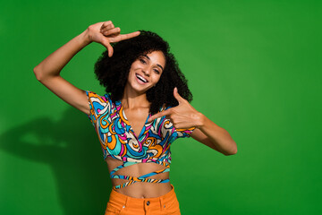 Photo of young girl content creator know how to find better view for portrait making frame gesture isolated on green color background