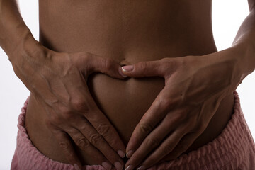 Close-up of woman's hands making a heart on her stomach