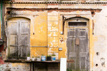 Detail of derelict wooden doors and windows and peeling paint on the wall of an old heritage house...