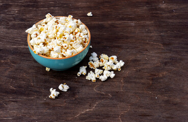 A plate of popcorn on a brown table , top view.