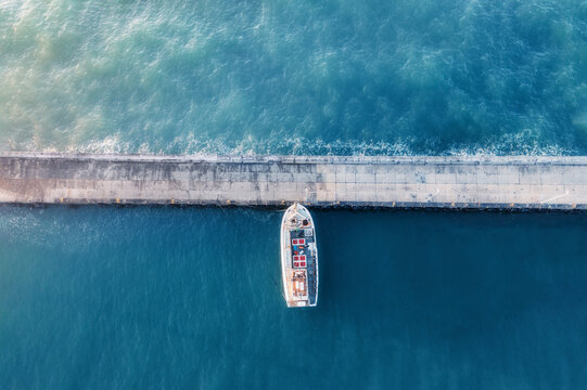 Aerial view of a fishing boat docked in a harbour, with blue water, creating a minimalist image, Cape Town, Western Cape, South Africa.