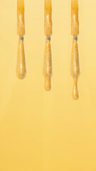 Gotas de esmalte de uñas dorado sobre fondo de color amarillo 
