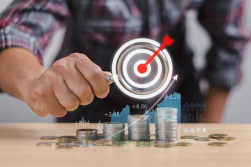 investor or trader holding magnifying glass with target icon pointing at coin overlaid with graph...