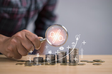 Concept of interest rate and dividend, man holding a magnifying glass with percentage signs showing savings, income, investment, taxes, dividends Stock market and investment return,Banking Finance