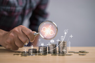 Concept of interest rate and dividend, man holding a magnifying glass with percentage signs showing...