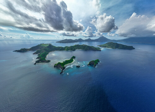 Aerial View of lush Masare and Pahepa Island with pristine beaches on a partly cloudy day in front of Siau, Indonesia.