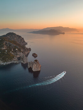 Aerial view of Capri Island at sunset, view of the Faraglioni rock formation along the coastline, Capri, Naples, Campania, Italy.