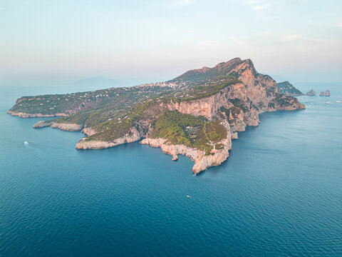 Aerial view of Capri Island at sunset, view of the Faraglioni rock formation along the coastline, Capri, Naples, Campania, Italy.