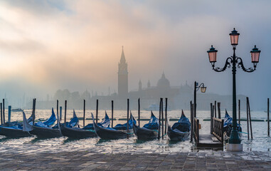 Gondolas in Venice at sunrise in morning fog. Veneto, Italy..