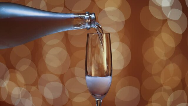 botella de champagne llena vaso vac&iacute;o. El fondo es dorado con efecto de luz bokeh.