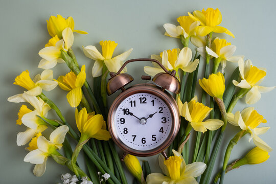Alarm clock with spring flowers top view. Spring time, daylight savings concept, spring forward