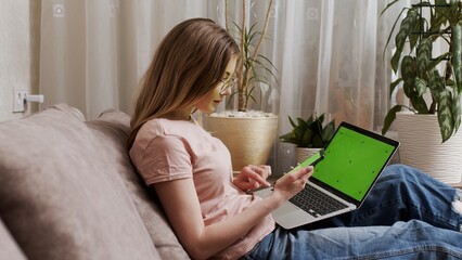Woman using green screen smartphone with Chromakey laptop. Close-up of a woman holding a mobile...
