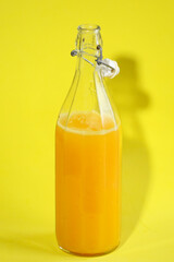 Bottle of orange soda with yellow background