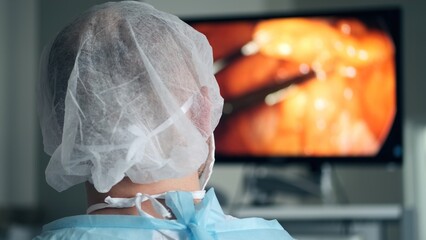 The operating surgeon looks at a large screen in the operating room during surgery. Modern...